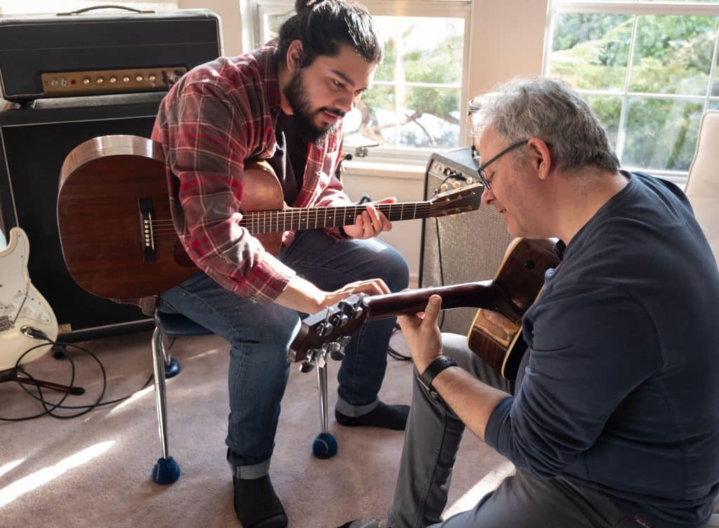 Adult student learning guitar with an experienced guitar teacher